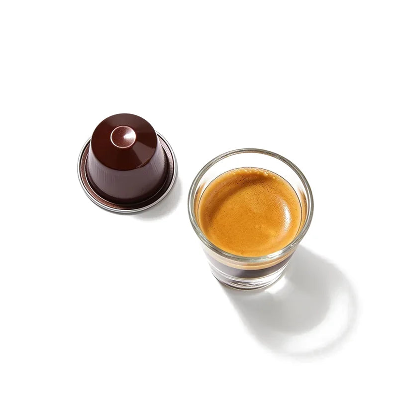 An espresso capsule beside a small espresso cup