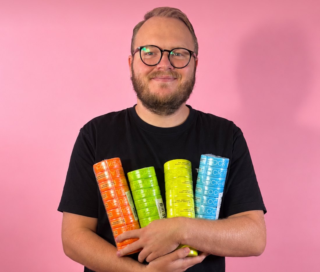 Killrådet-profil i svart t-shirt håller staplar med SZN-dosor i fyra smaker mot rosa bakgrund